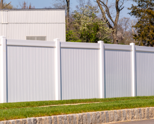 white vinyl picket fence on green lawn surrounding property grounds for backyard protection and privacy